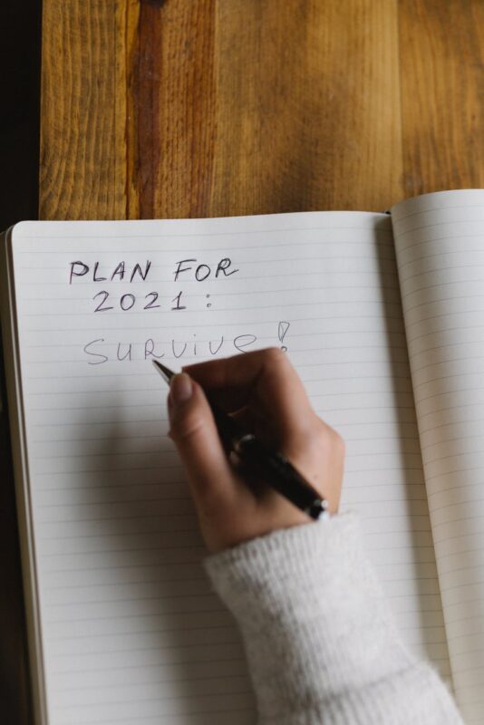 unrecognizable woman taking notes in planner with pen